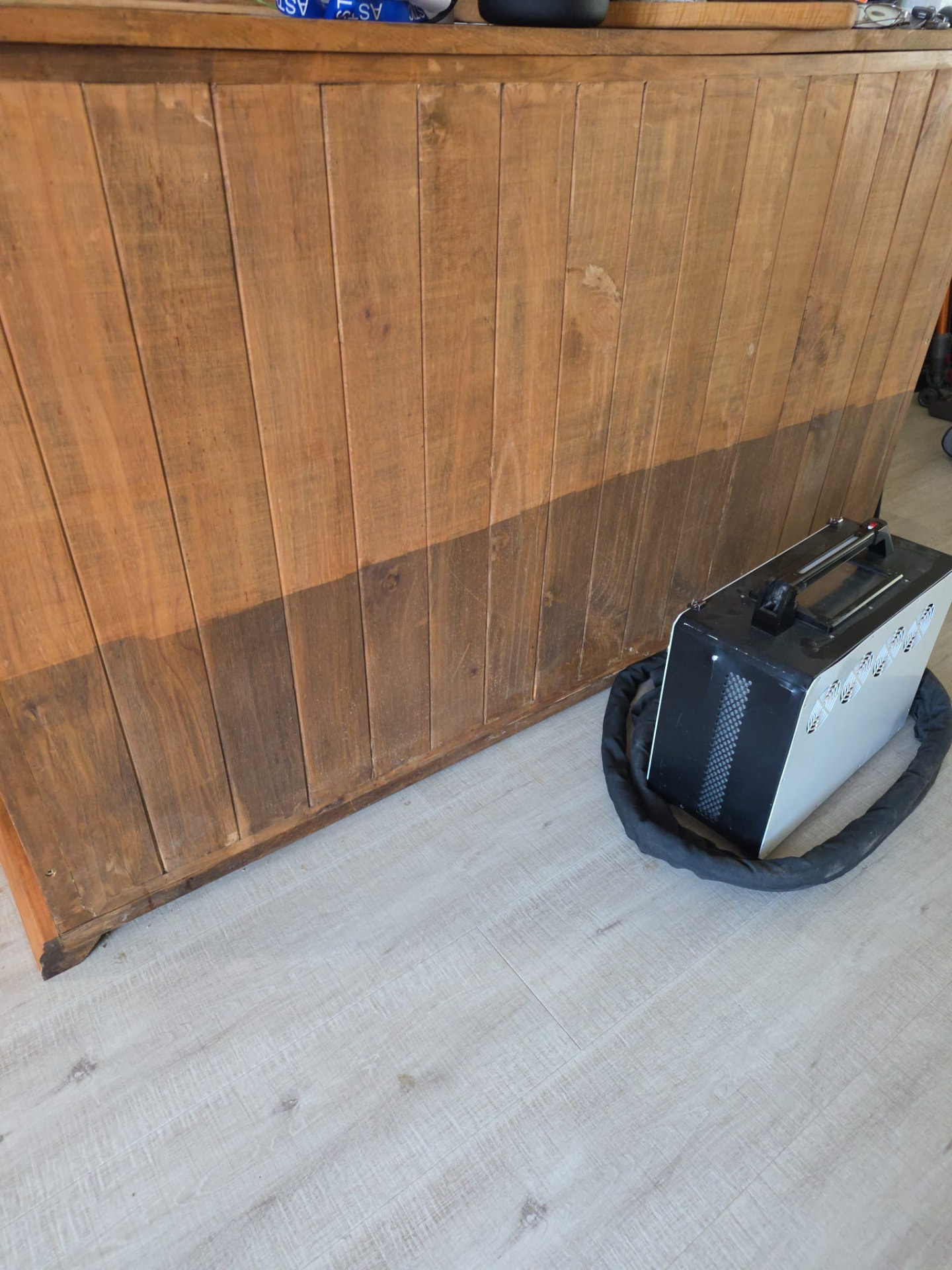Décapage laser en cours sur un meuble en bois